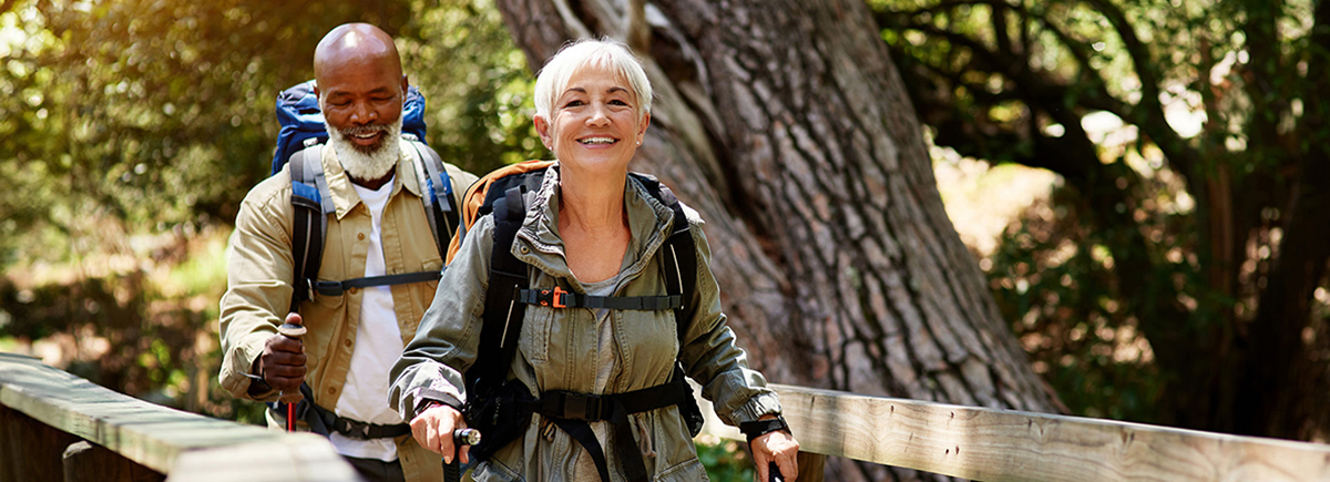 mature couple hiking across bridge