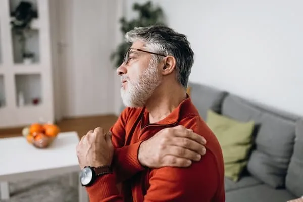 older man holding painful shoulder